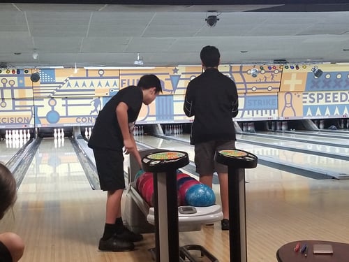 Middle School boys picking up balls at the bowling lanes
